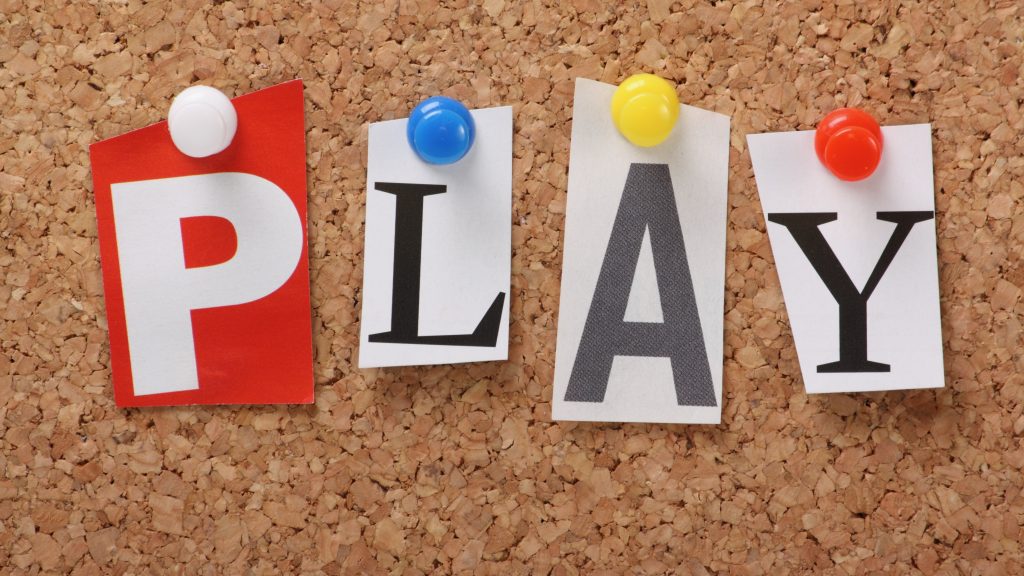 A close up of the word play pinned to a corkboard. Learn about the benefits of play from a play therapist in Atlanta, GA with North Atlanta Psychotherapy. We offer therapy for men in Atlanta, GA, play therapy for kids in Atlanta, GA, and more!