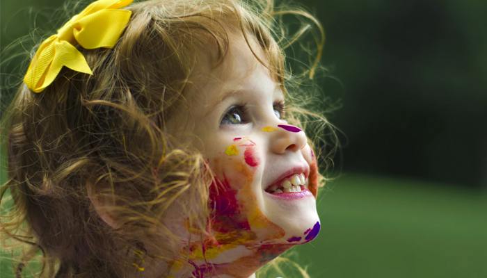 A close up of a child smiling with paint on their face. This could symbolize the benefits of play therapy in Atlanta, GA can offer. Learn more about play therapy for kids in Atlanta, GA today.