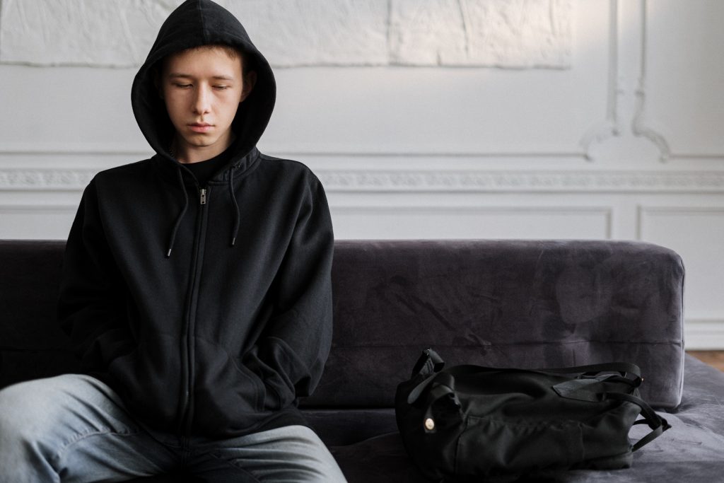 A teen sits wearing a black hoodie and a grim expression. Learn how grief counseling in Atlatna, GA can offer support by contacting a grief counselor in Atlanta, GA. We can offer bereavement counseling in Atlanta, GA and other services including online grief counseling in Atlanta, GA today.